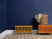 Mercury 4 Column Cast Iron radiator on tilted floor and dark blue wall in Farrow and Ball Citron.