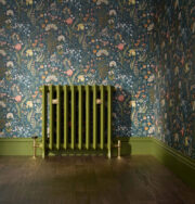 Emmeline II traditional cast iron radiator 670mm high in Farrow and Ball Bancha Green paint colour on floral wall paper and wooden floor