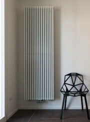 Vasco Zana Vertical Designer Radiator finished in textured white in living space with wicker chair