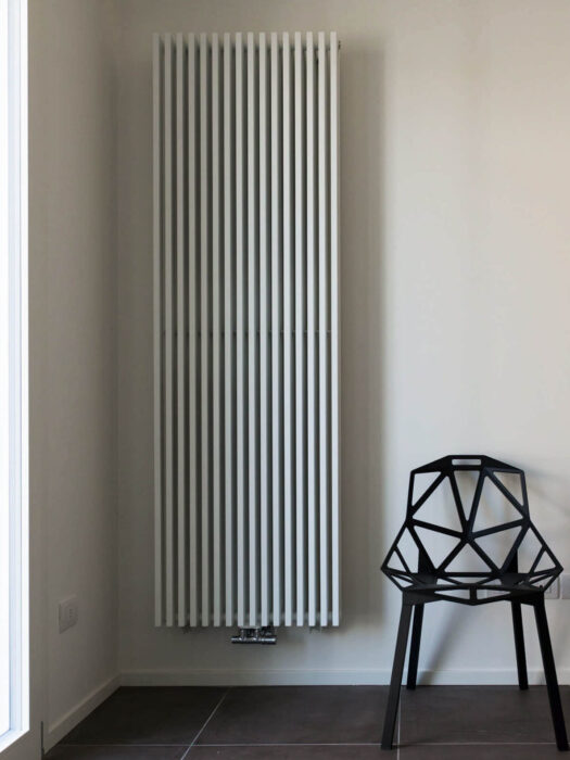 Vasco Zana Vertical Designer Radiator finished in textured white in living space with wicker chair