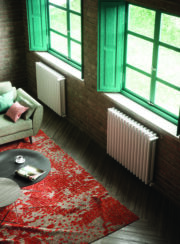 two Cordivari Arianna radiators low under windows finished in white with red carpet