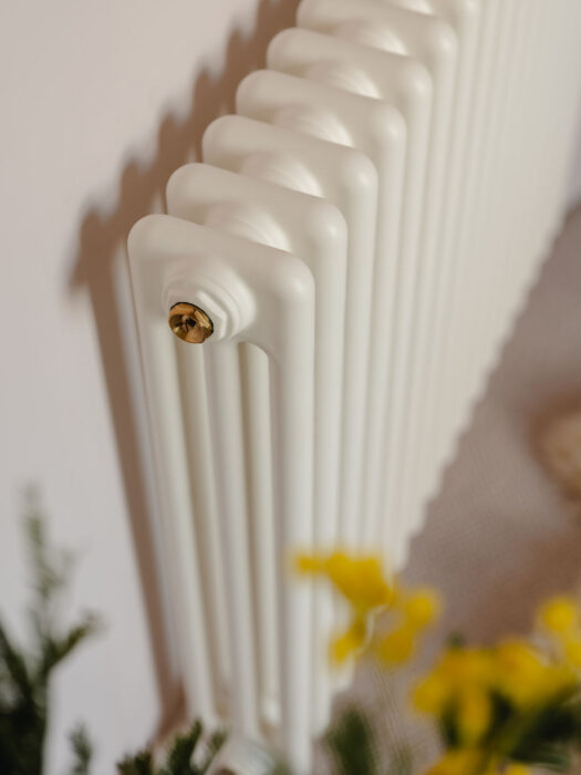 Milky white 2 column Tuba steel radiator on pale pink wall