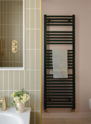 Green bathroom towel rail shown against pale green tiles and blush pink wall