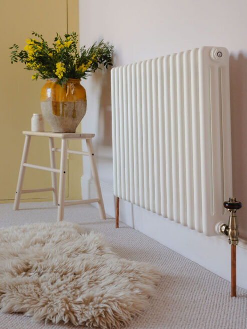 Traditional steel horizontal radiator in white shown against yellow paintwork