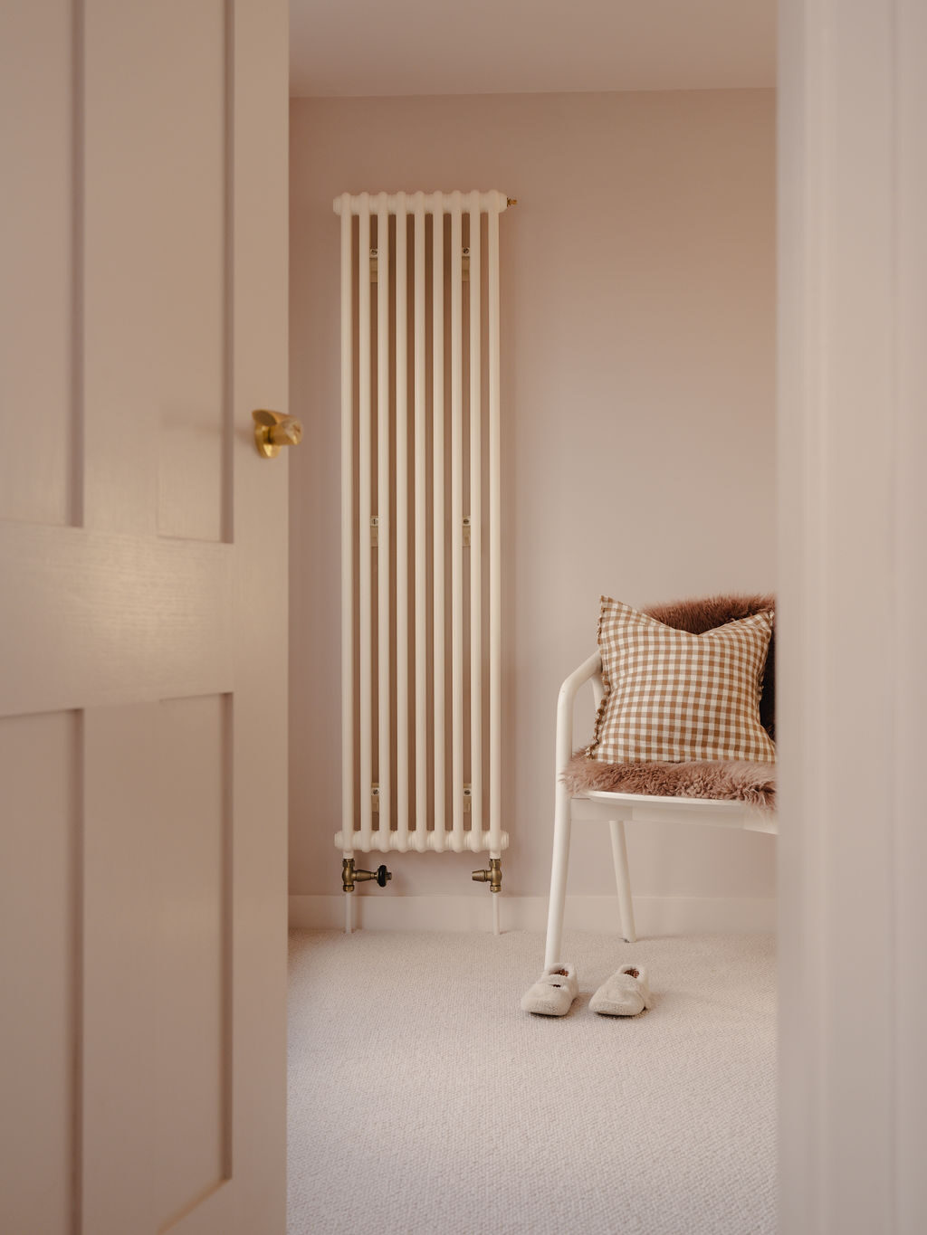 Milky White Tuba vertical radiator shown in bedroom with putty colour walls