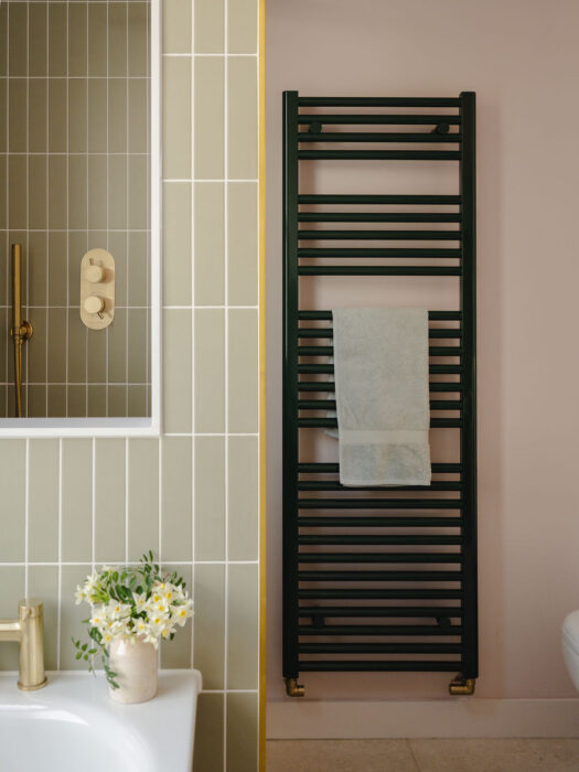 Green bathroom towel rail shown against pale green tiles