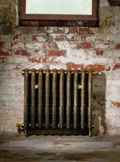 Aged Gold Ornate Rococo II Cast Iron radiator in old brick work hall