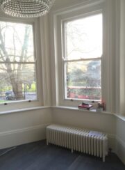 White Tuba 6 Column traditional style radiator in angled bay window on feet