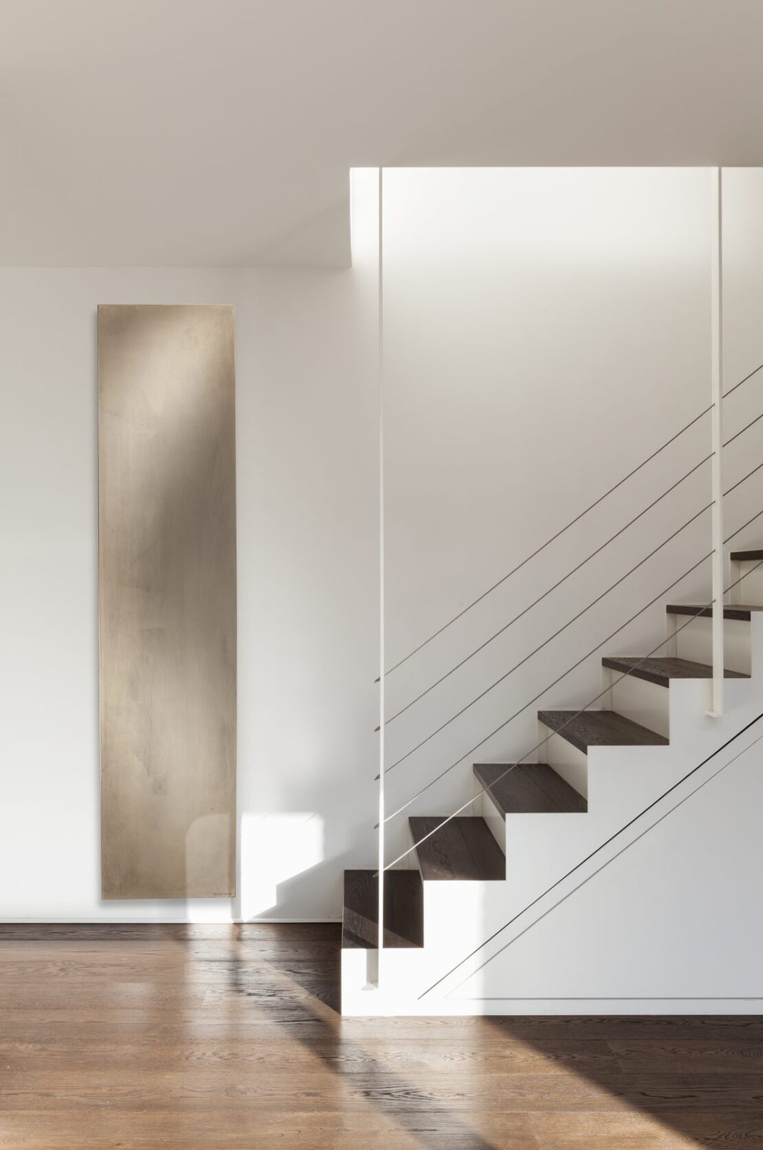 Cinier Uni Beige Stone Vetical radiator by open staircase and wooden floor