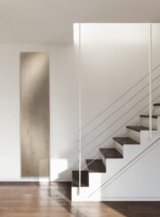 Cinier Uni Beige Stone Vetical radiator by open staircase and wooden floor