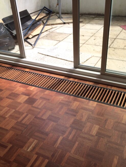 Varnished Merbau Dark Wooden Mini Canal Trench Heating Grille with dark Wooden parquet flooring and patio