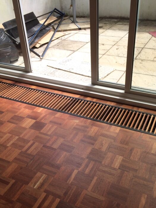 Varnished Merbau Dark Wooden Mini Canal Trench Heating Grille with dark Wooden parquet flooring and patio