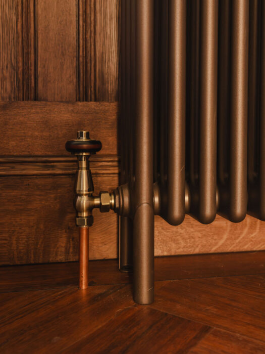 Vintage thermostatic radiator valves in antique brass on old bronze radiator