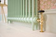 RadCen Traditional Thermostatic TRV Valve Set in Unlaquered Brass Finish with Black Wooden Control Head on Green Cast Iron Radiator